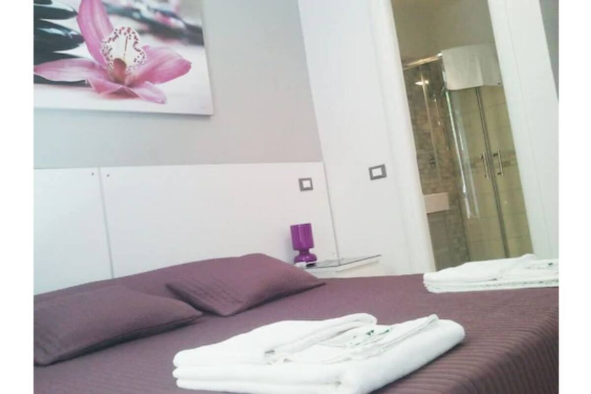 Une chambre à coucher avec un lit, des oreillers et une serviette blanche pliée.