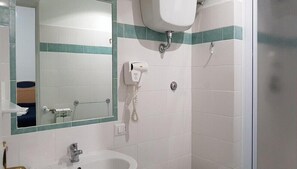 Une salle de bain équipée d’un lavabo, d’un miroir et d’un sèche-cheveux fixé au mur.