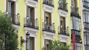 A yellow building with multiple balconies, each with a black wrought iron railing and potted plants. - Hostal Oriente (Madrid)
