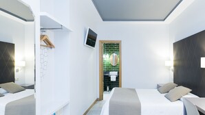 A modern hotel room with two beds, a TV, and a bathroom visible through a door. - Hostal Oriente (Madrid)