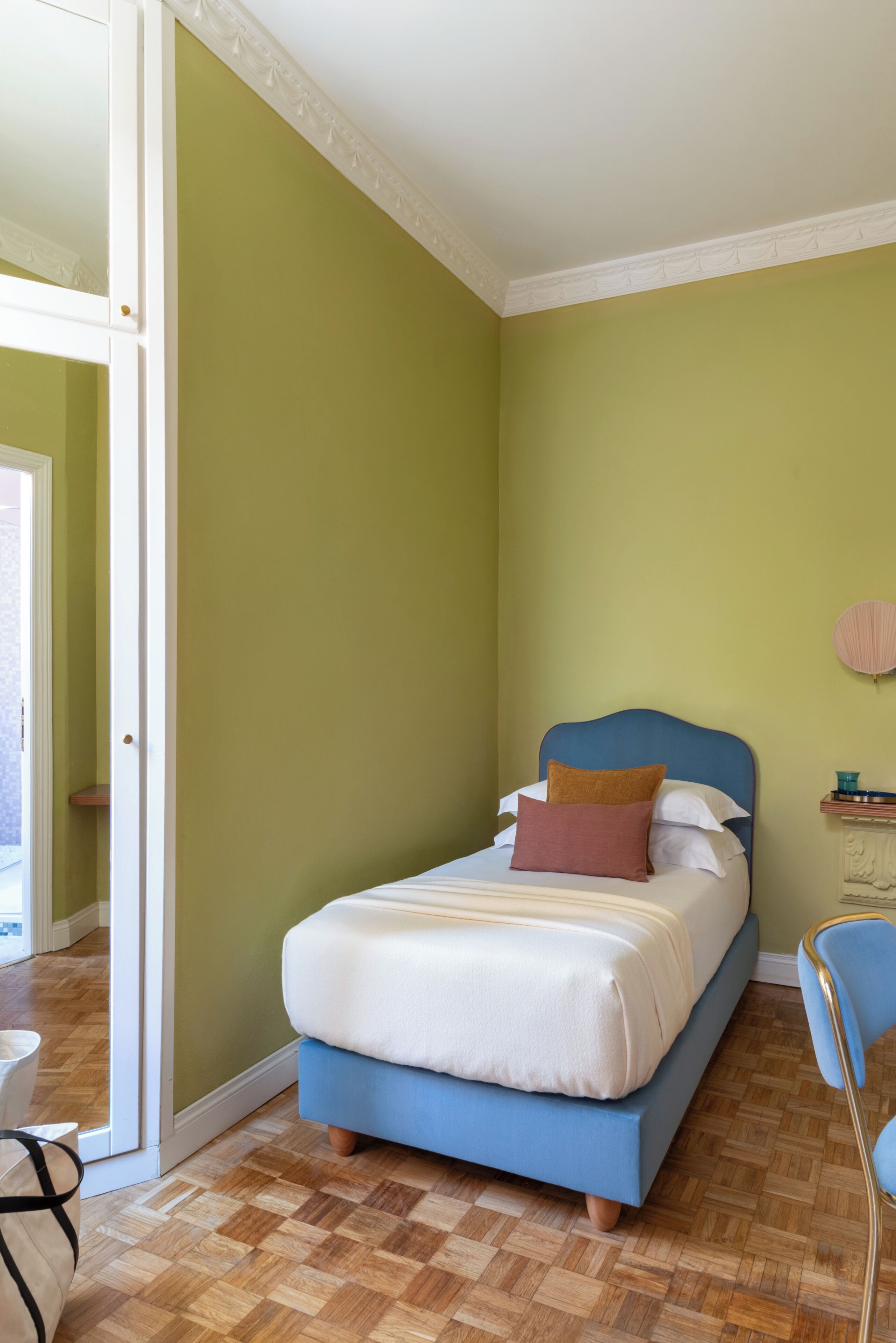 A bedroom with a bed, a chair, and a door leading to another room.