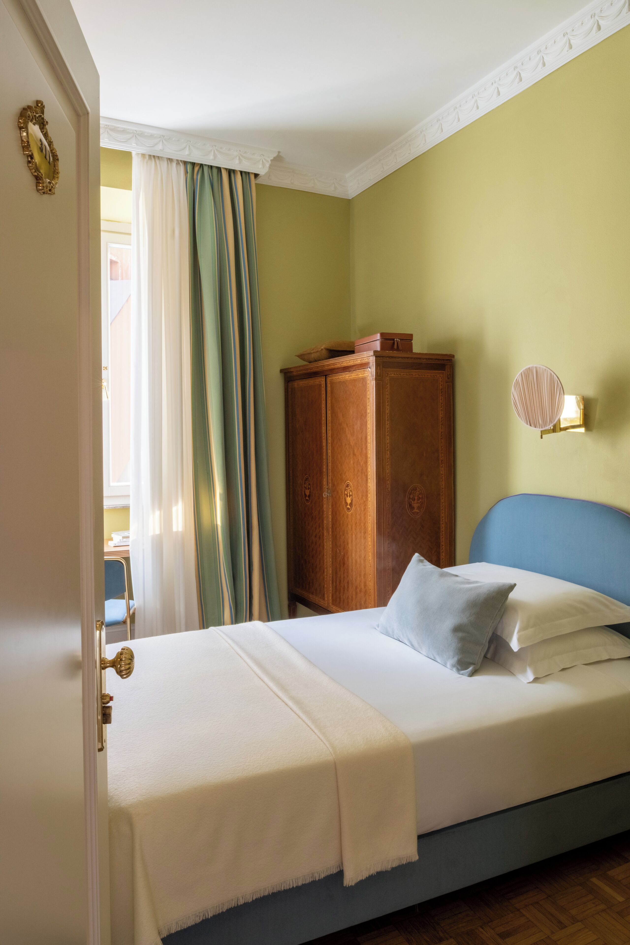 Ein Schlafzimmer mit Bett, Kleiderschrank, Lampe und Blick nach draußen.