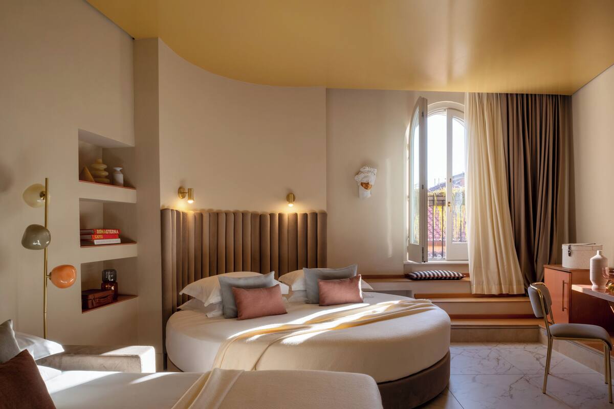 Ein modernes Hotelzimmer mit einem großen Bett, Nachttischen, einem Schreibtisch und einem Fenster mit Vorhängen.