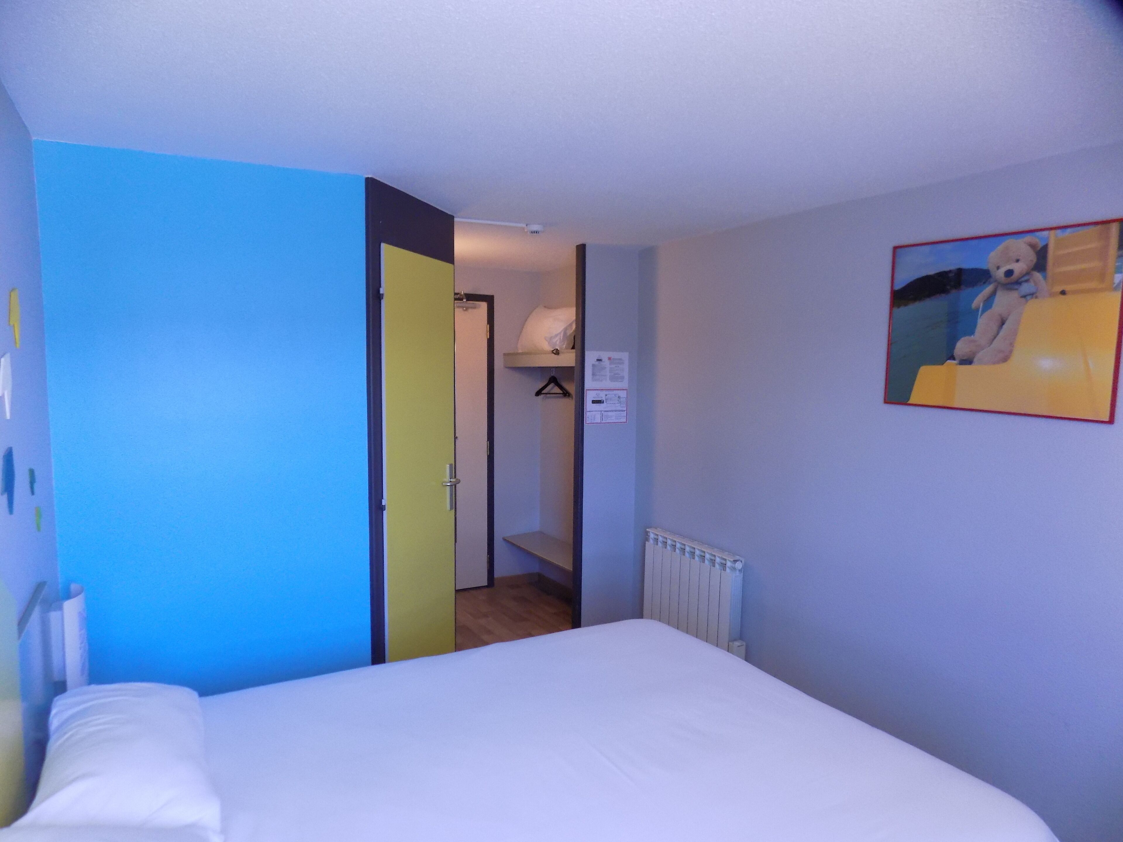 A bedroom with a bed, a door leading to a bathroom, and a wall with a painting.