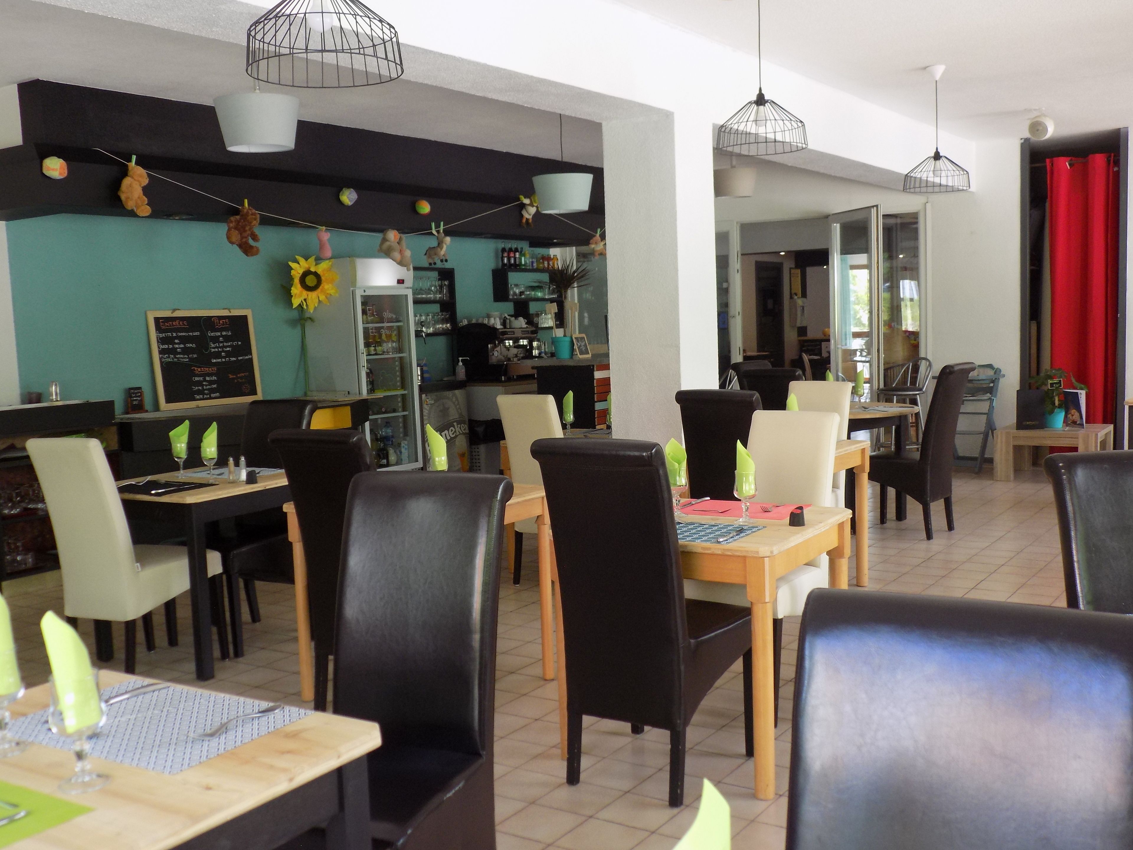 A restaurant with multiple tables and chairs, a menu board, and hanging decorations.