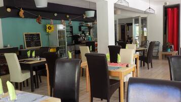 A restaurant with multiple tables and chairs, a menu board, and hanging decorations.