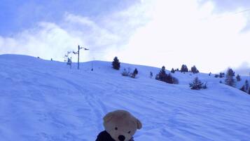 Un osito de peluche sentado sobre un trineo rojo en un paisaje nevado.