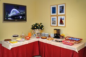 Ein Buffet mit verschiedenen Speisen und einem Fernseher, der eine Stadtansicht zeigt.