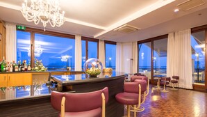 A bar area with a bar counter, bar stools, and a chandelier.