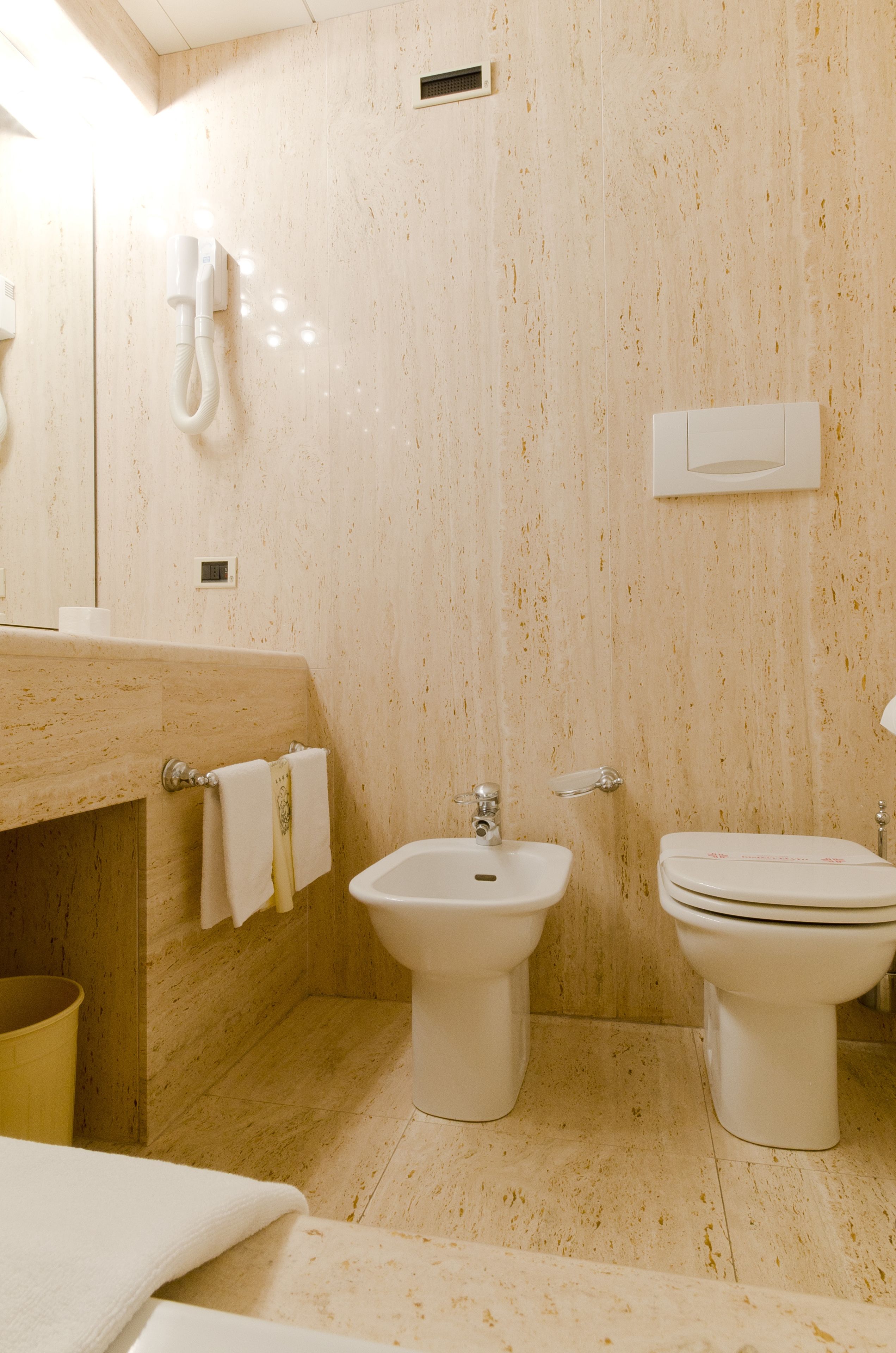 A bathroom with a bidet, a toilet, a sink, and a mirror.