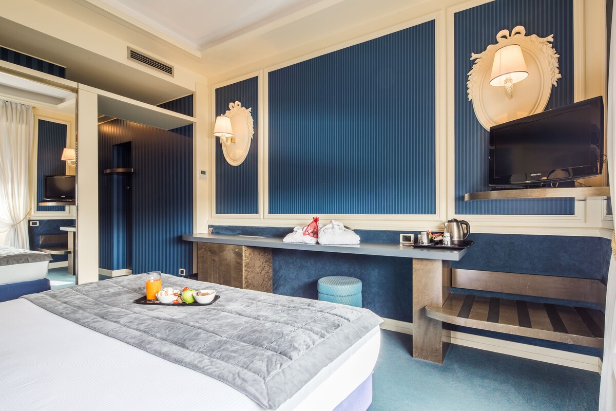 Hotellihuone, jossa on sänky, työpöytä, televisio ja taustalla näkyy kylpyhuone.