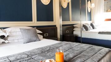A hotel room with a large bed, bedside tables, a mirror, and a tray with food and a glass of orange juice.