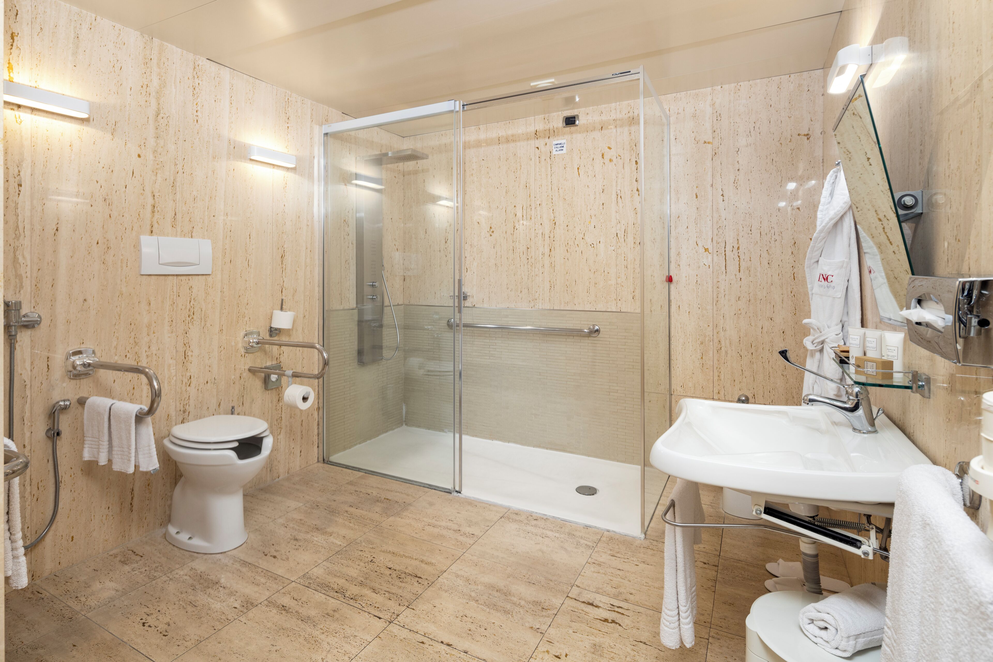 Une salle de bain moderne avec une douche à parois de verre, des toilettes blanches et un lavabo avec un miroir.