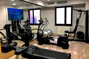 A gym with treadmills, elliptical machines, and exercise balls.