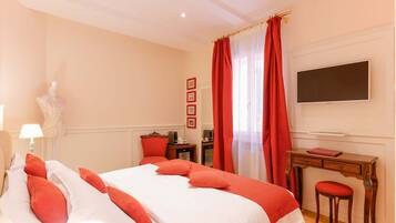 Una habitación de hotel con una cama, un escritorio, una silla, un televisor y una lámpara.