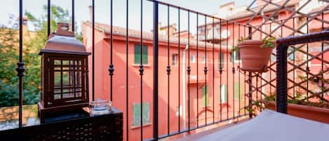A balcony with a metal railing, a small table with a lantern, and a potted plant.