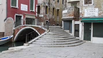 Un estrecho canal veneciano con un puente que lleva a una escalera.