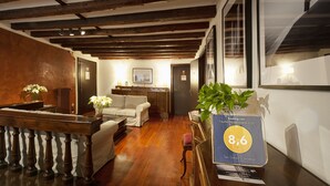 Un hall d’hôtel avec des poutres en bois, un canapé, une table à manger et une plaque commémorative encadrée.