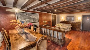 Un coin repas avec une table et des chaises en bois, un vase rempli de fleurs et un grand tableau encadré accroché au mur.