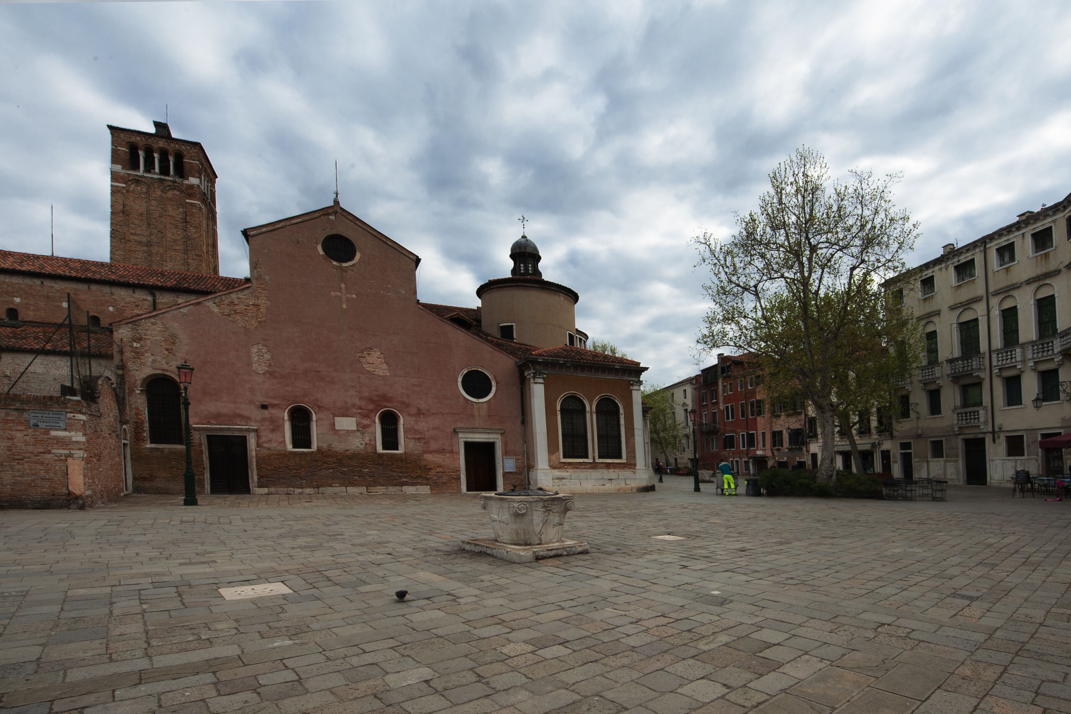 Un bâtiment historique doté d’un clocher et d’un dôme central, entouré d’une place pavée.