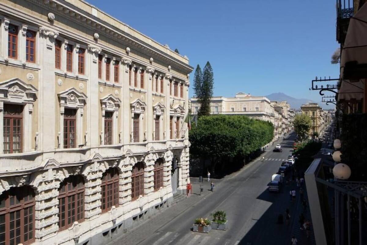 A street view with classical architecture, a clear sky, and a distant mountain.