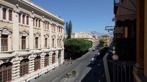 Vista de una calle con arquitectura clásica, cielo despejado y una montaña distante.
