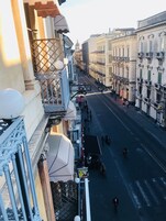 Una strada fiancheggiata da edifici, con balconi dotati di ringhiere e passanti.
