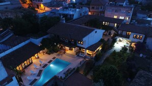 Vista aérea de una zona residencial con piscina, varias casas y un patio bien iluminado.