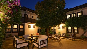 An outdoor patio area with seating arrangements, a potted plant, and a tree providing shade. - Villa Konak Hotel (Kusadasi)