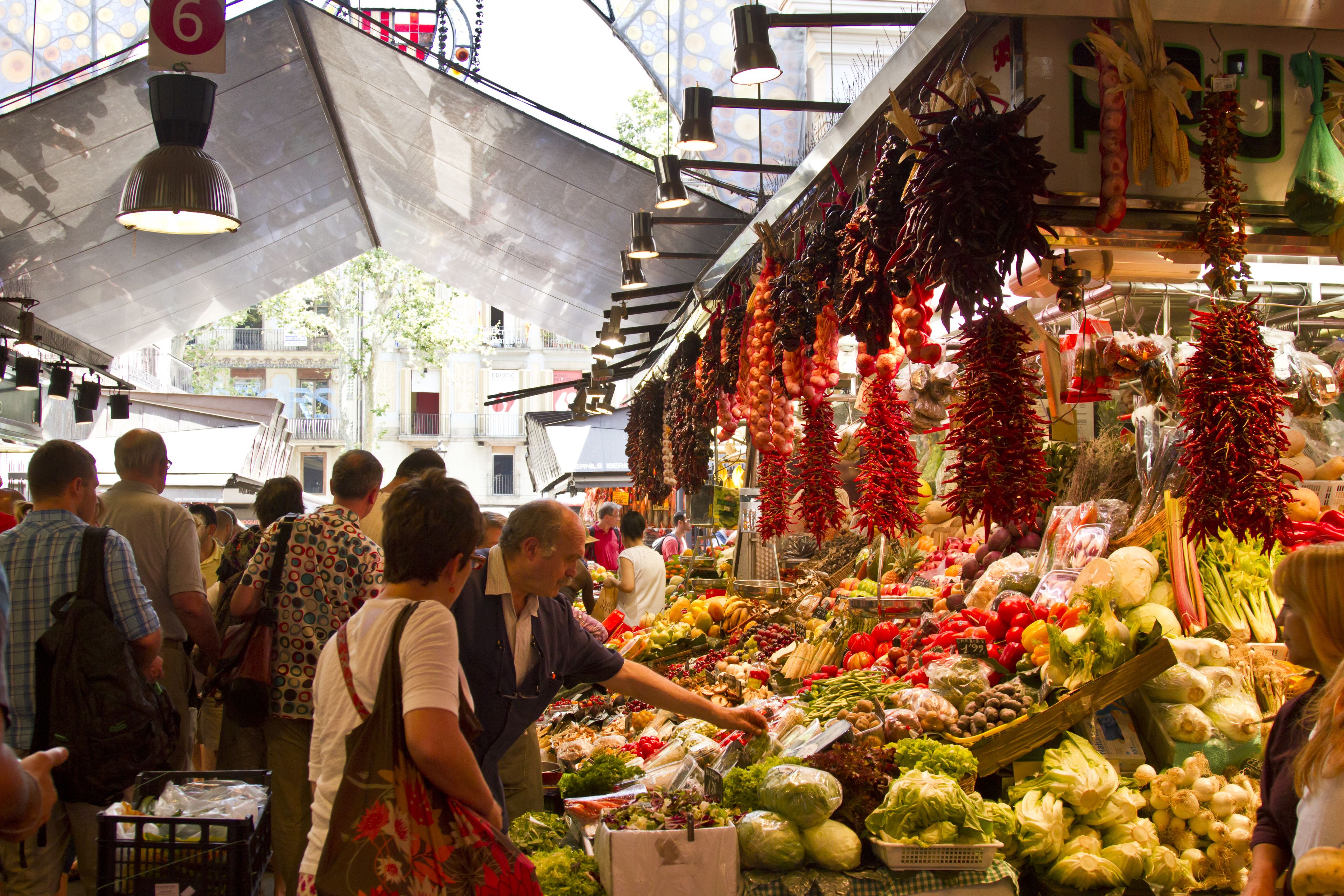 Un marché couvert animé où l’on trouve une grande variété de produits frais et d’articles suspendus, mis en vente.