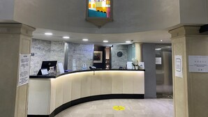 Zona de recepción con mostrador curvo, un reloj en la pared y un ventanal de vitral.