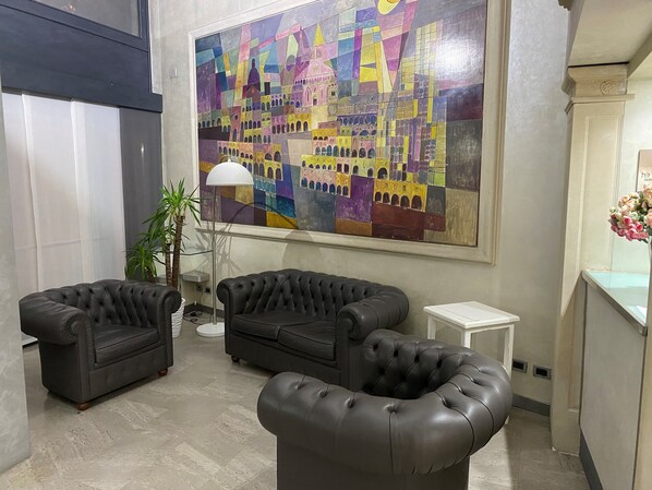A lobby with two black leather sofas, a floor lamp, and a large abstract painting on the wall. - Hotel Europa (Padova)