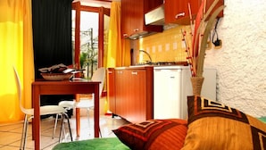 A compact kitchen with wooden cabinets, a white stove, and a small refrigerator. - Solemare b&b - Apartments Alghero (Alghero)