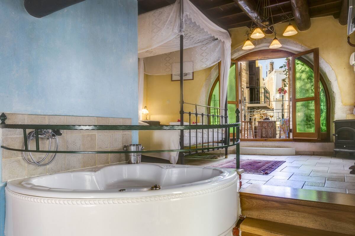 A bathroom with a freestanding bathtub, a glass shower enclosure, and a view of a balcony with outdoor furniture.
