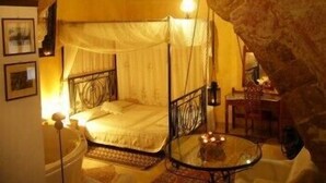 A cozy, dimly lit room with a bed, a small table, and a chair. - Ifigenia Rooms & Studios (Chania)