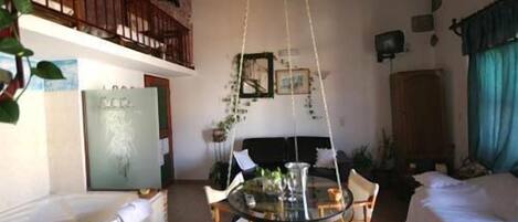 A room with a glass table, chairs, a bed, a bathtub, and a balcony with a railing.