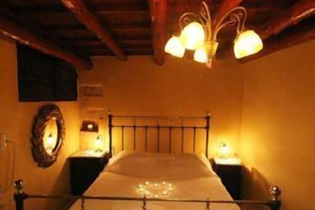 A wooden-framed bed with a headboard, two bedside tables, and a wall-mounted mirror.