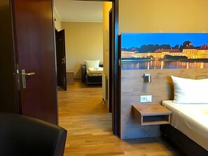 Habitación de hotel con cama, una mesita de noche de madera, una silla y vista a un edificio a través del agua.