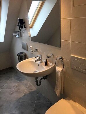 Un baño moderno con un lavamanos independiente, un perchero y un espejo.