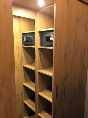 A wooden wardrobe with multiple shelves and two electronic devices on the top shelf.
