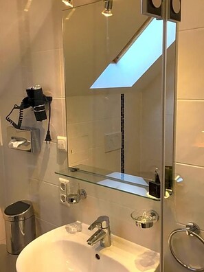 A modern bathroom with a large mirror, skylight, and a glass shelf. - Parkhotel Leiser (Planegg)