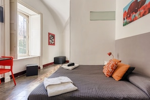 A bedroom with a bed, a desk, a chair, and a window.