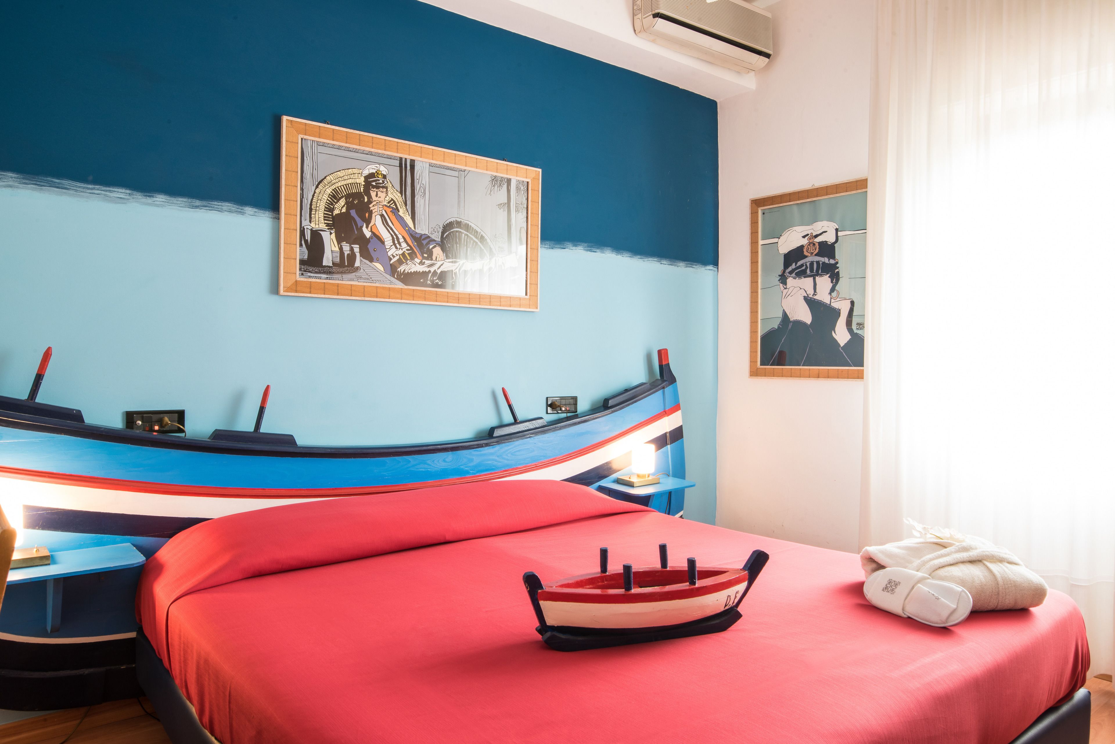 A room with a bed, a small table, and a wall with two framed pictures.