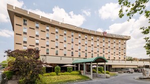 Een hotel met een groot, beige gevel, meerdere ramen en een entreegebied met een groen dak.