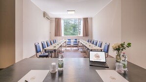 Een vergaderruimte met een lange tafel, blauwe stoelen en een laptop waarop het logo van de hotelgroep staat.