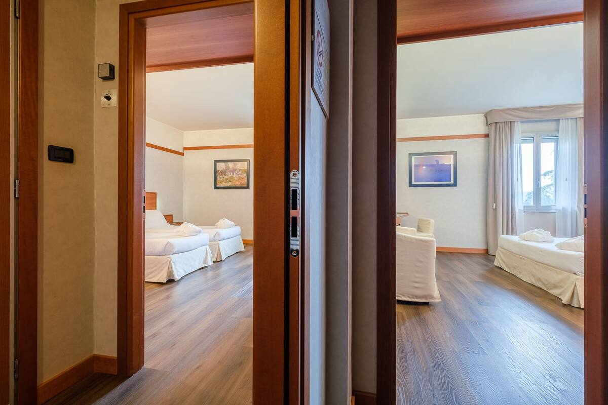 Een hotelkamer met twee bedden, een kleine tafel en een schilderij aan de muur.
