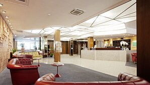 Een moderne lobby met leren banken, een receptiebalie en een groot raam dat voor natuurlijk licht zorgt.