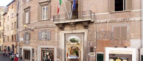 A historic building with a central entrance, multiple windows, and flags.
