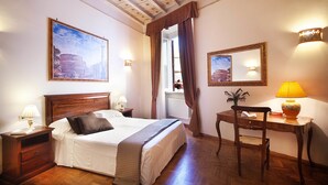 A neatly arranged bedroom with a bed, bedside tables, a desk with a lamp, a chair, and a large window with curtains. - Pantheon Inn (Rome)