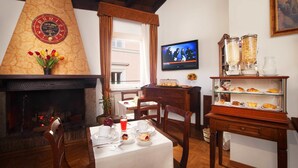 A dining area with a fireplace, a television, and a display case with pastries. - Pantheon Inn (Rome)